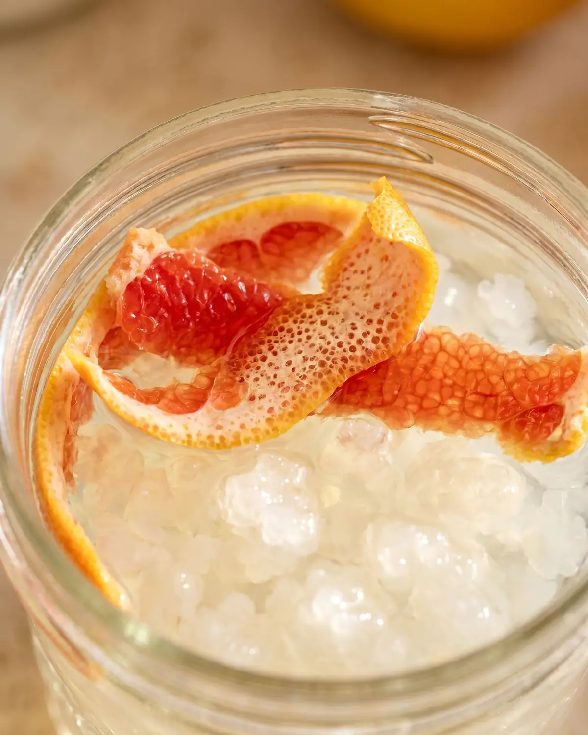 water kefir drink Detail van pompelmoesschil die op waterkefir drijft, met zachte bubbels en korrels onder het oppervlak