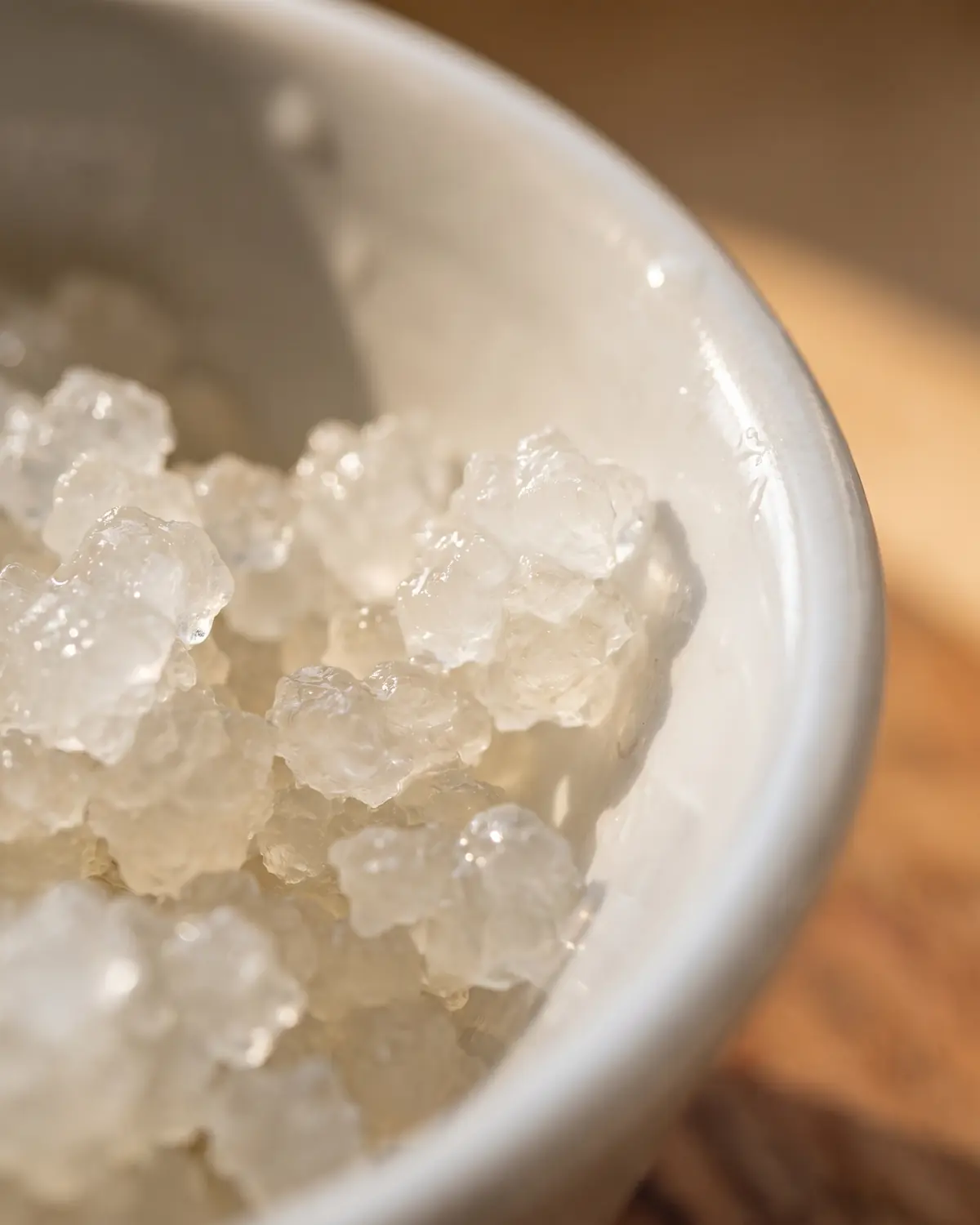 tweede fermentatie waterkefir Macrobeeld van gelatineachtige waterkefirkorrels tegen nat wit keramiek, met doorschijnende structuren.